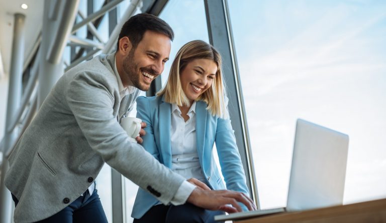 Shot of two happy young businesspeople enjoying working on a laptop.